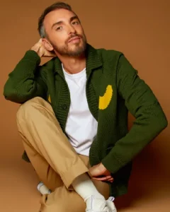 Christophe Willem sur fond ambré, veste verte, pantalon beige